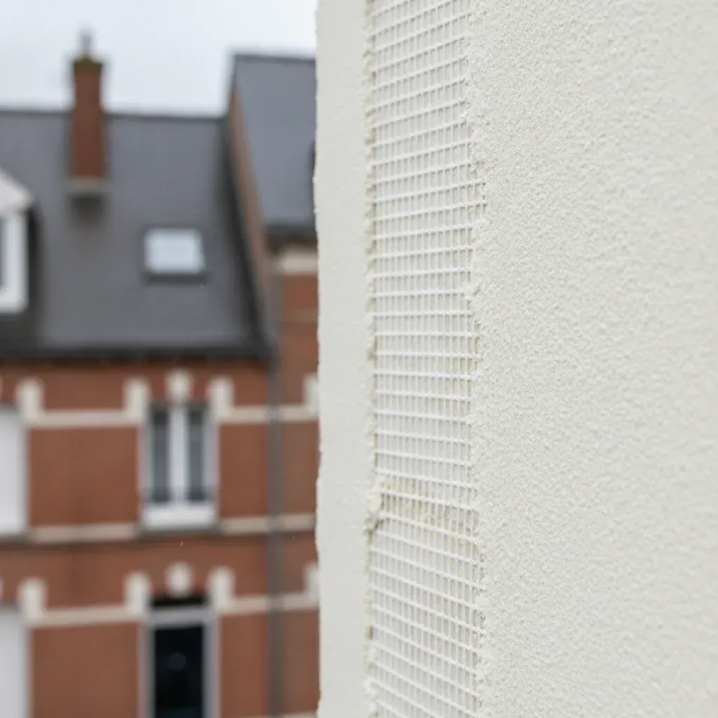 Application d'un enduit minéral à la chaux sur une trame de renfort d'isolation.